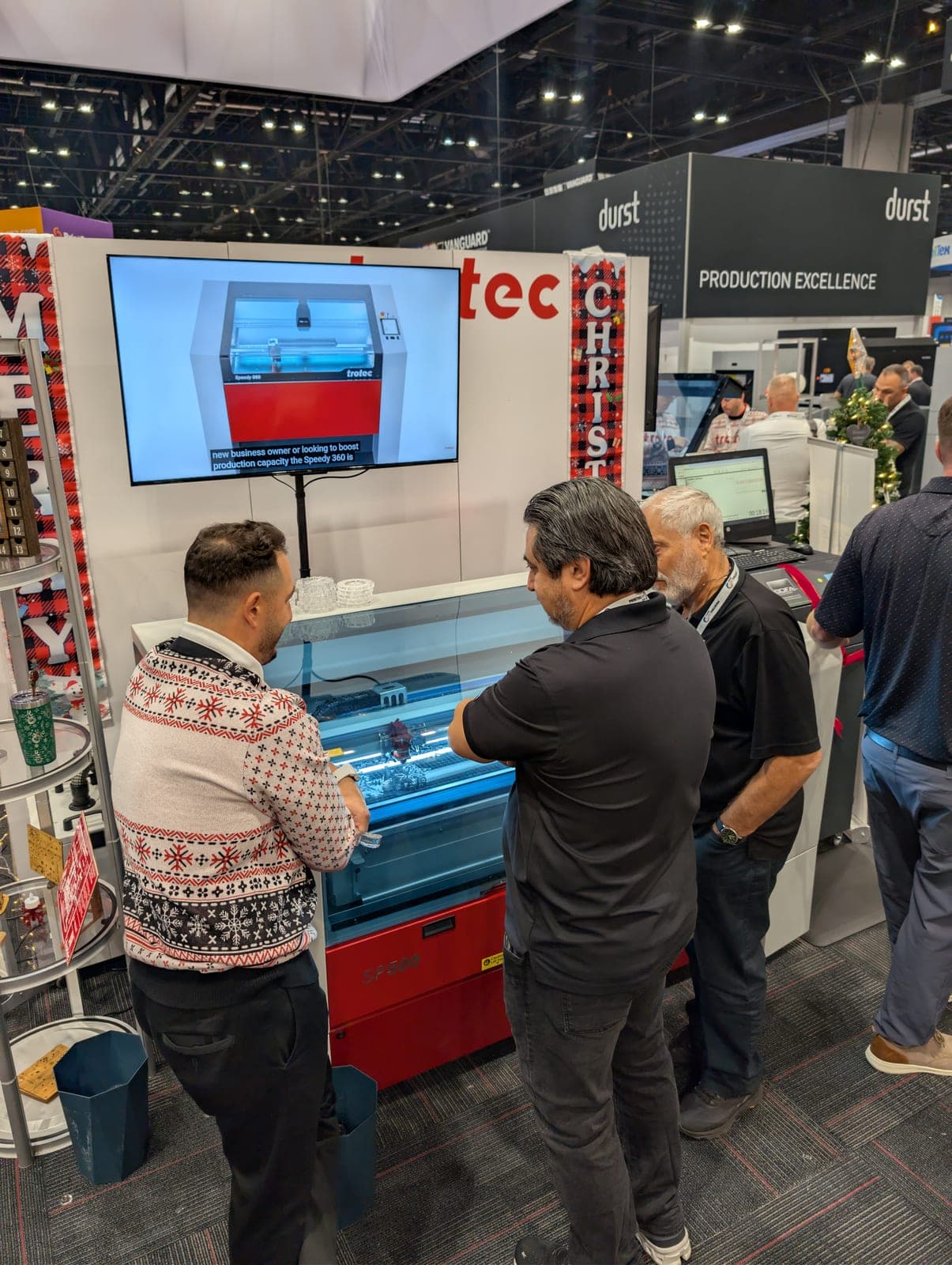 PressTech demonstrating a Trotec Speedy laser to customers at a trade show