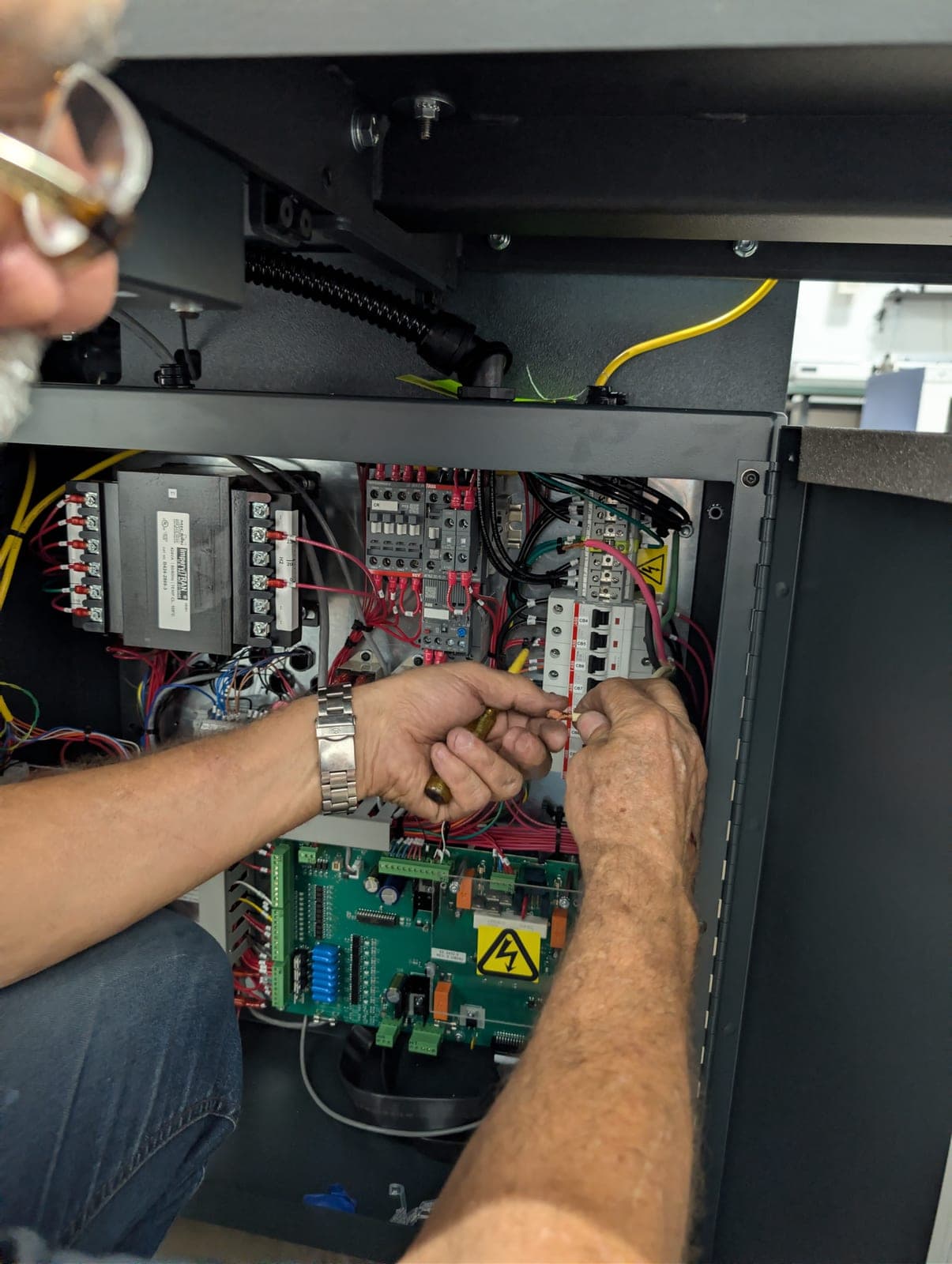 PressTech technician troubleshooting the control panel of a print finishing machine